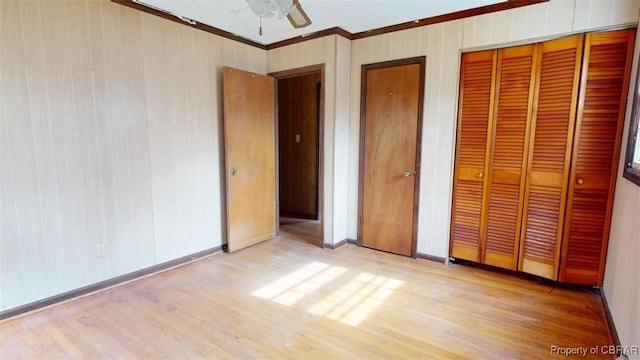 unfurnished bedroom featuring ornamental molding, ceiling fan, light wood-style flooring, and baseboards