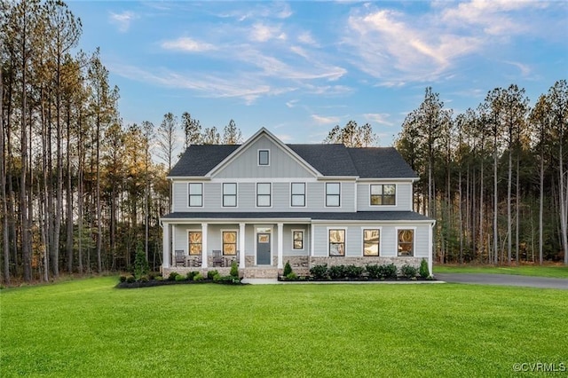 view of front facade with stone siding, a porch, board and batten siding, and a front yard