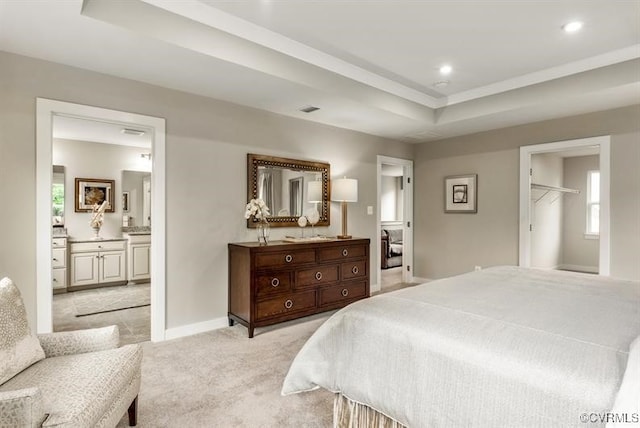 bedroom featuring baseboards, a raised ceiling, light colored carpet, ensuite bathroom, and recessed lighting