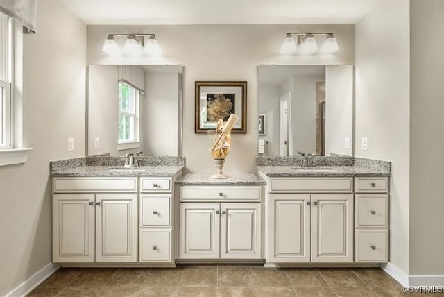 full bath with double vanity, baseboards, and a sink