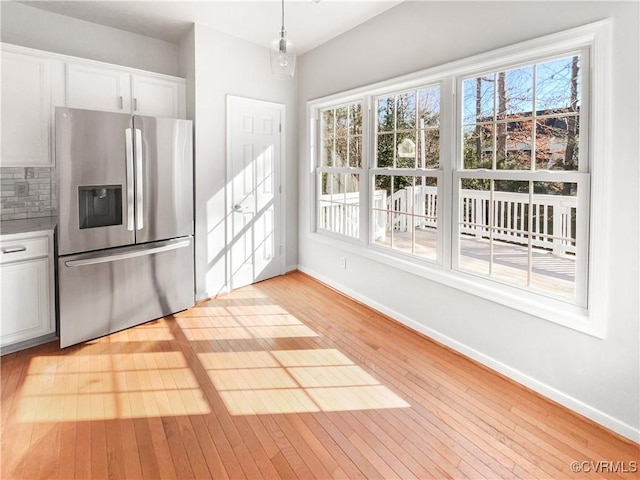 kitchen with backsplash, light wood-type flooring, stainless steel fridge, and white cabinetry