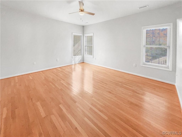 spare room with a ceiling fan, baseboards, visible vents, and light wood finished floors