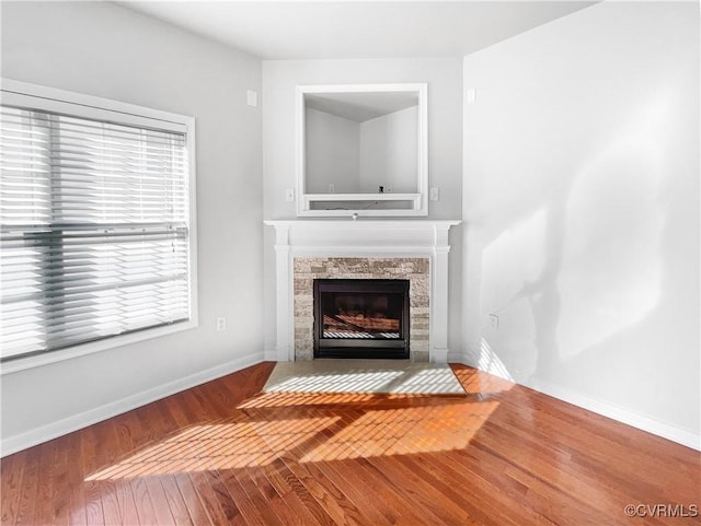 unfurnished living room featuring a fireplace, baseboards, and wood finished floors