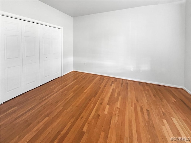 unfurnished bedroom with a closet, baseboards, and wood finished floors