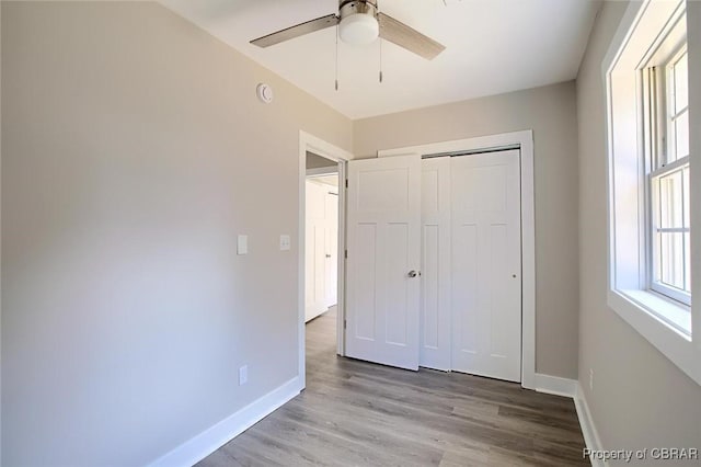 unfurnished bedroom featuring light wood finished floors, ceiling fan, baseboards, and a closet