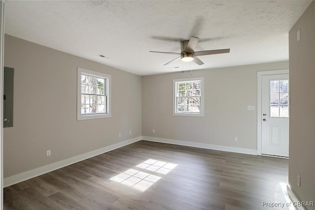 empty room with dark wood-style floors, visible vents, baseboards, and a textured ceiling