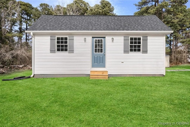 view of front facade featuring a front yard, roof with shingles, and entry steps