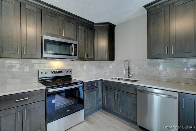 kitchen featuring light countertops, appliances with stainless steel finishes, a sink, and tasteful backsplash