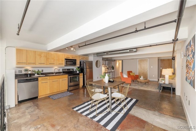 kitchen with stainless steel appliances, dark countertops, light brown cabinets, a sink, and concrete flooring