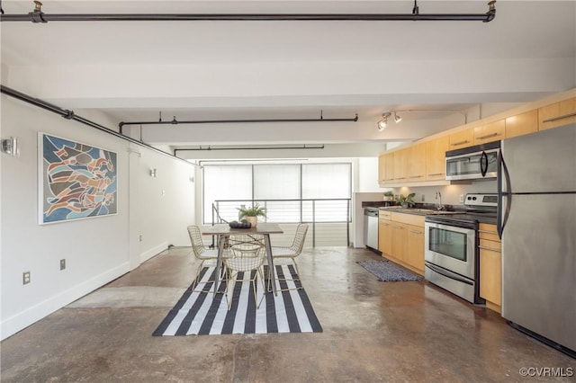 kitchen featuring dark countertops, light brown cabinetry, appliances with stainless steel finishes, finished concrete floors, and baseboards