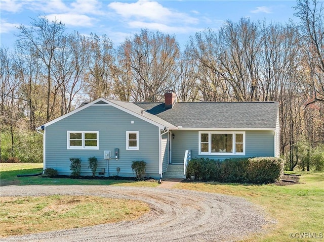 ranch-style home featuring driveway, a chimney, a front lawn, and a shingled roof