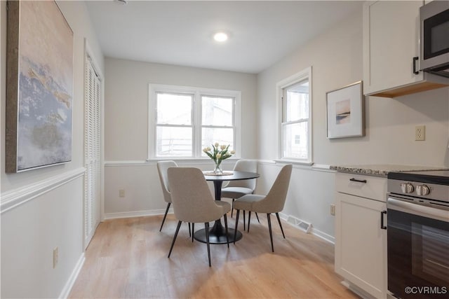 dining area featuring light wood-style flooring, visible vents, and baseboards