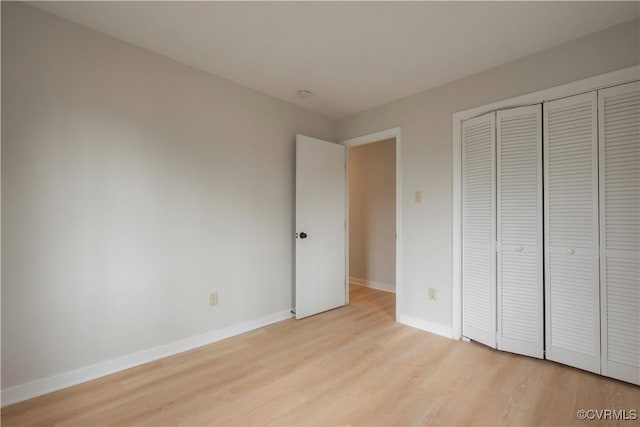 unfurnished bedroom featuring a closet, baseboards, and light wood finished floors