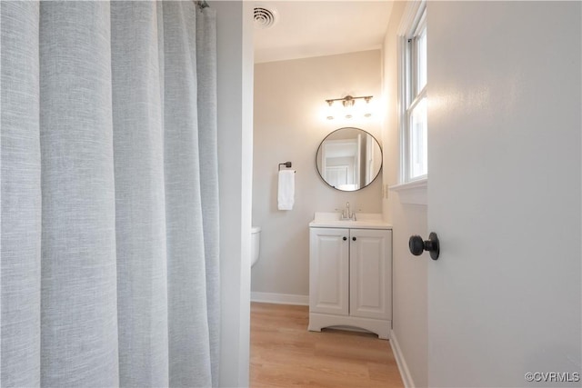 bathroom with baseboards, visible vents, toilet, wood finished floors, and vanity