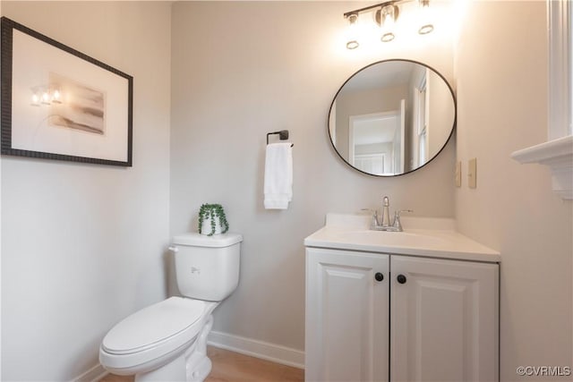 bathroom featuring baseboards, vanity, and toilet