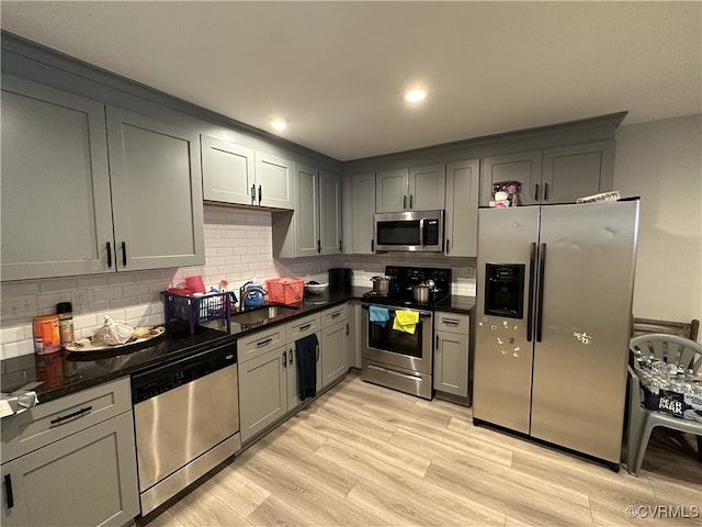 kitchen featuring gray cabinetry, appliances with stainless steel finishes, decorative backsplash, and light wood-style floors