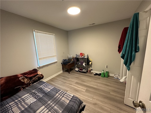 bedroom featuring visible vents, light wood-style flooring, and baseboards