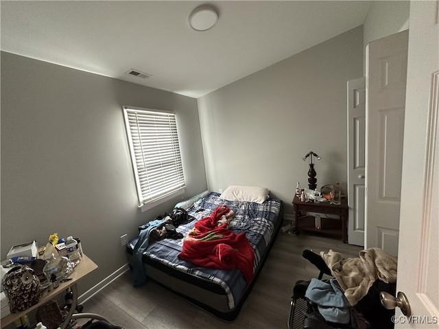 bedroom with lofted ceiling, dark wood-type flooring, and visible vents