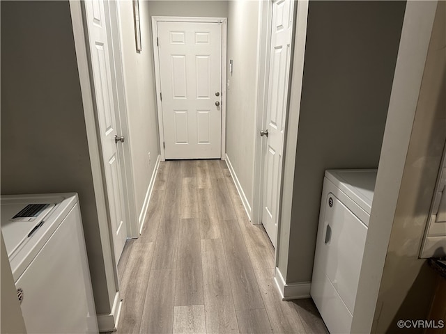 clothes washing area with light wood-style floors, laundry area, independent washer and dryer, and baseboards