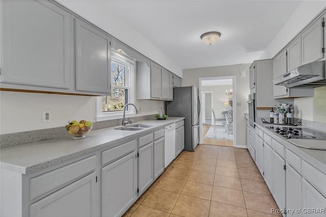 kitchen featuring light tile patterned flooring, under cabinet range hood, stainless steel appliances, a sink, and light countertops