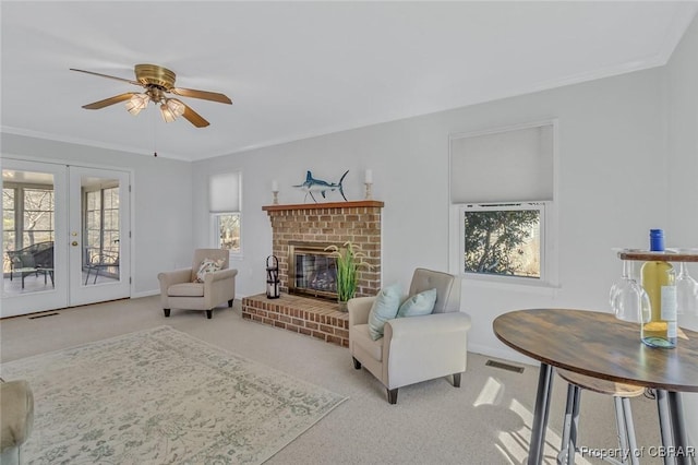 living room featuring light carpet, visible vents, crown molding, french doors, and a brick fireplace