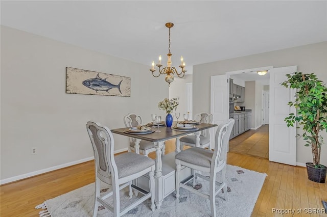 dining area featuring baseboards, a chandelier, and light wood-style floors