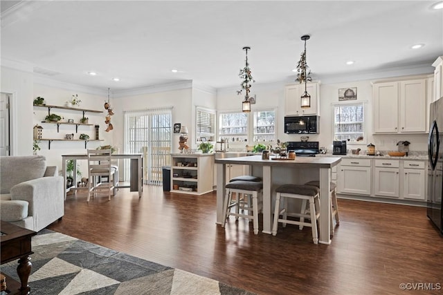 kitchen with plenty of natural light, black appliances, dark wood-style floors, and light countertops