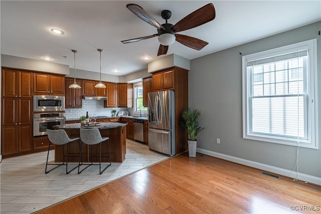 114 Cedar Works Row, Henrico, VA 23231 - kitchen featuring decorative backsplash, dark countertops, a kitchen breakfast bar, under cabinet range hood, and stainless steel appliances