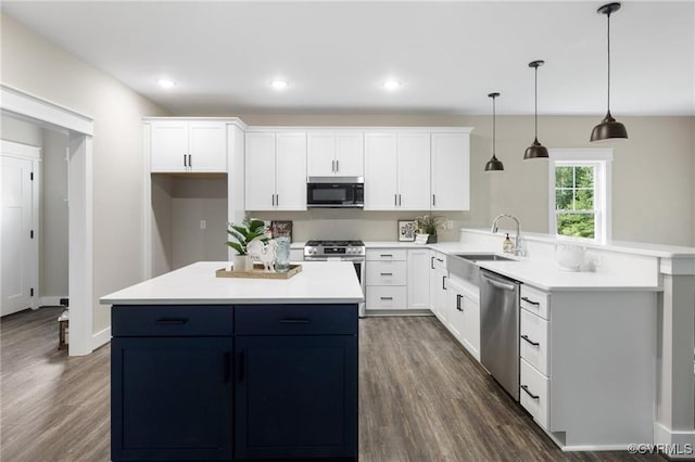 kitchen featuring decorative light fixtures, light countertops, appliances with stainless steel finishes, white cabinetry, and a sink