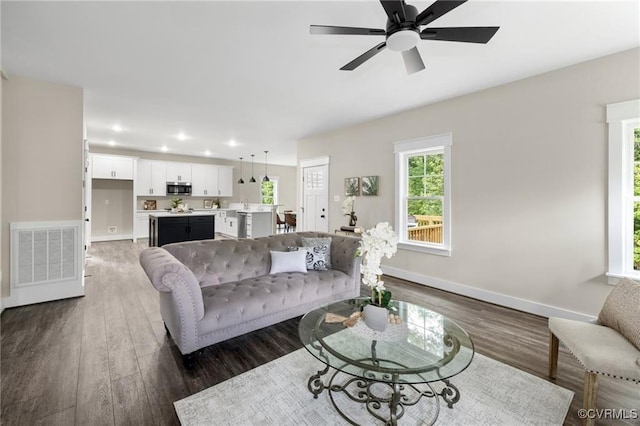 living area with baseboards, visible vents, ceiling fan, dark wood-type flooring, and recessed lighting