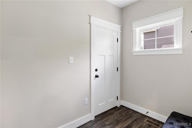 doorway with dark wood-style floors, visible vents, and baseboards