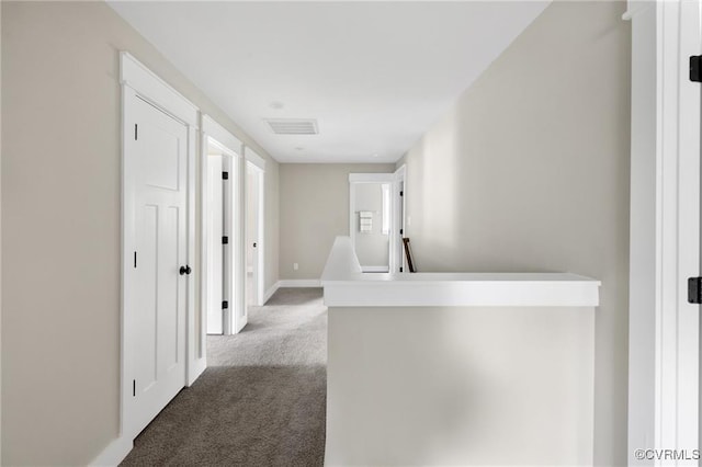 hallway with carpet, an upstairs landing, visible vents, and baseboards