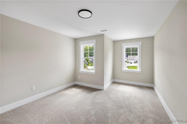 spare room featuring visible vents, light colored carpet, and baseboards