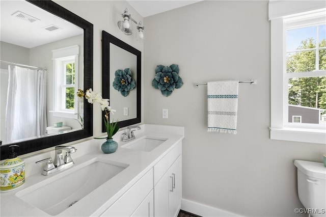 full bathroom with visible vents, double vanity, a sink, and toilet