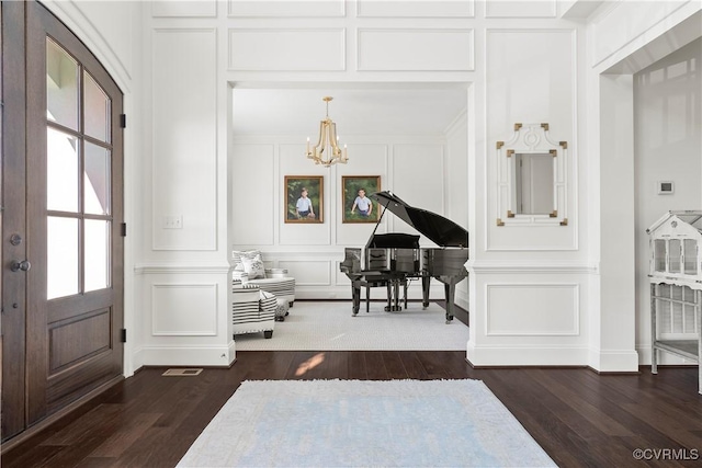 entrance foyer with a notable chandelier, dark wood-style floors, and a decorative wall