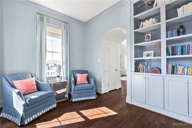 living area with dark wood-type flooring, arched walkways, ornamental molding, and baseboards