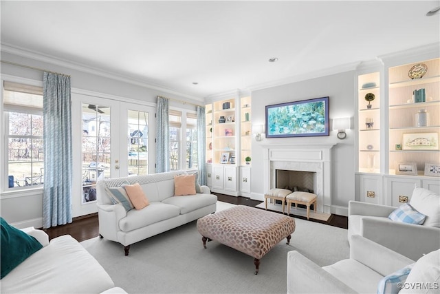 living room with baseboards, crown molding, french doors, built in shelves, and a high end fireplace