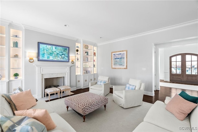 living room with french doors, crown molding, a high end fireplace, wood finished floors, and baseboards