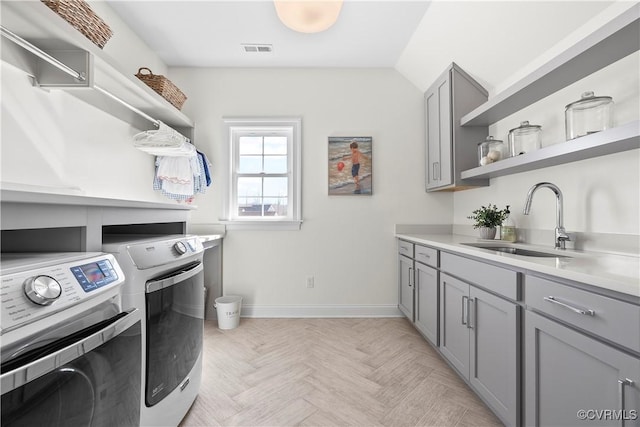 laundry area featuring cabinet space, visible vents, a sink, independent washer and dryer, and baseboards