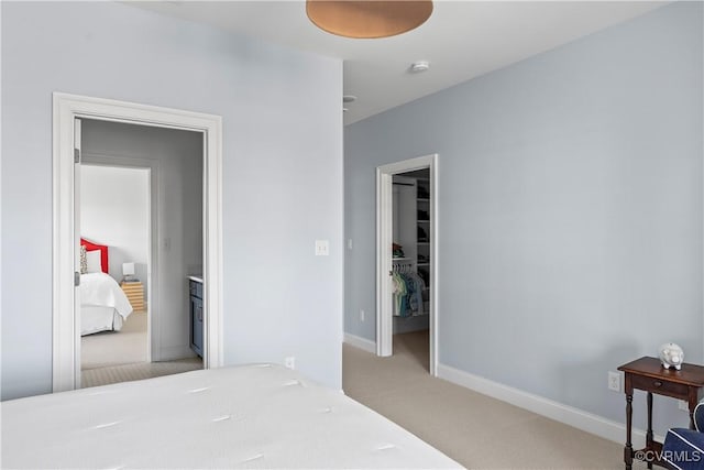 bedroom with baseboards, a spacious closet, a closet, and light colored carpet