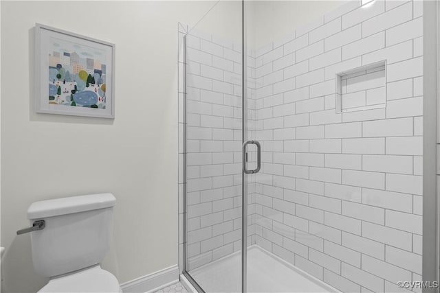 bathroom with a stall shower, toilet, and baseboards