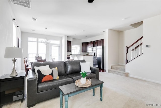 living area with light colored carpet, visible vents, plenty of natural light, and stairs