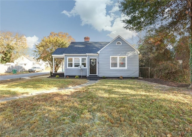 bungalow-style house with entry steps, a chimney, and a front lawn