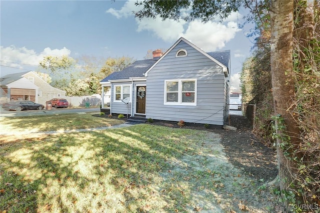 bungalow featuring entry steps, a chimney, fence, and a front yard