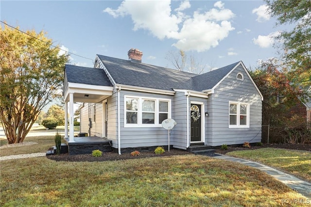 view of front facade featuring a chimney, a front lawn, and roof with shingles