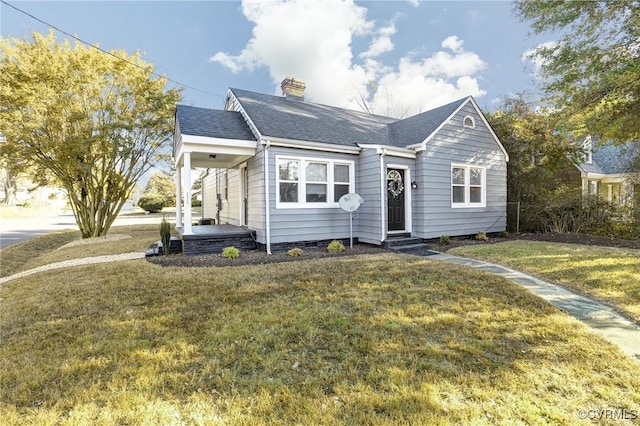 view of front of home with a front lawn, a chimney, and a shingled roof