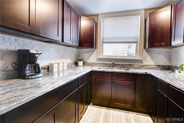 kitchen featuring light stone counters, a sink, and backsplash