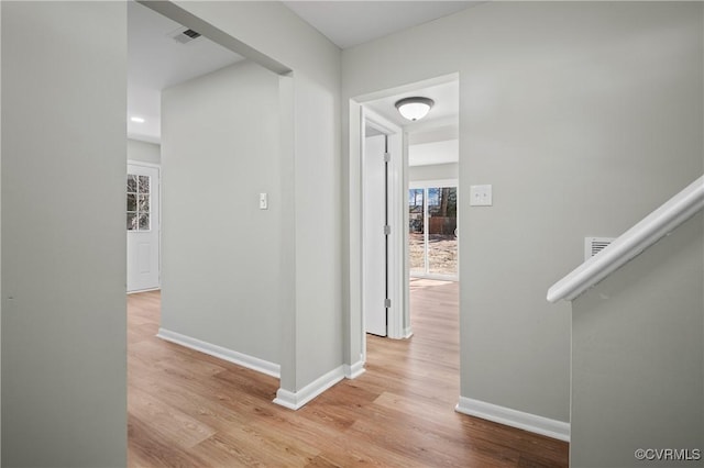 hall featuring light wood-style flooring and baseboards