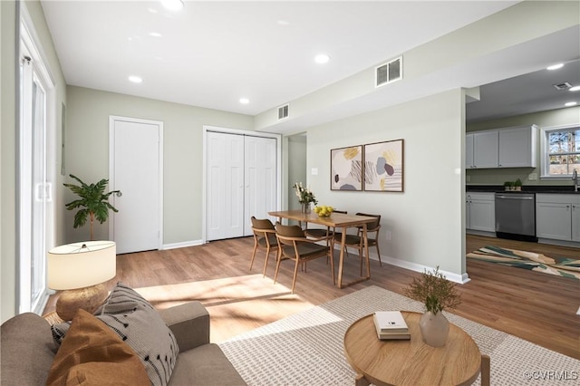 living room with light wood-style flooring, visible vents, and baseboards