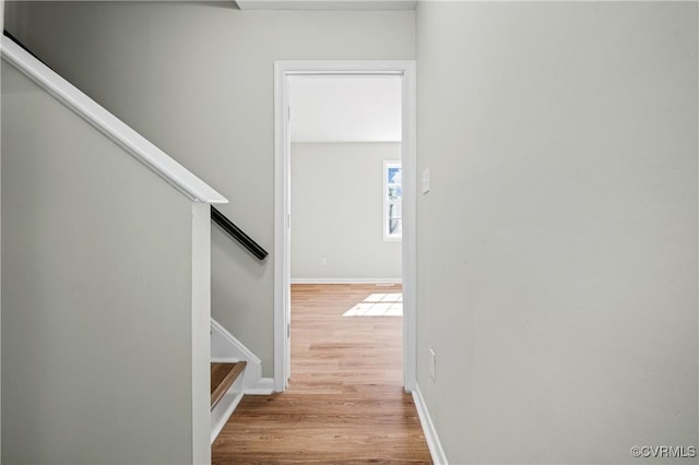 hall with stairs, light wood-style flooring, and baseboards